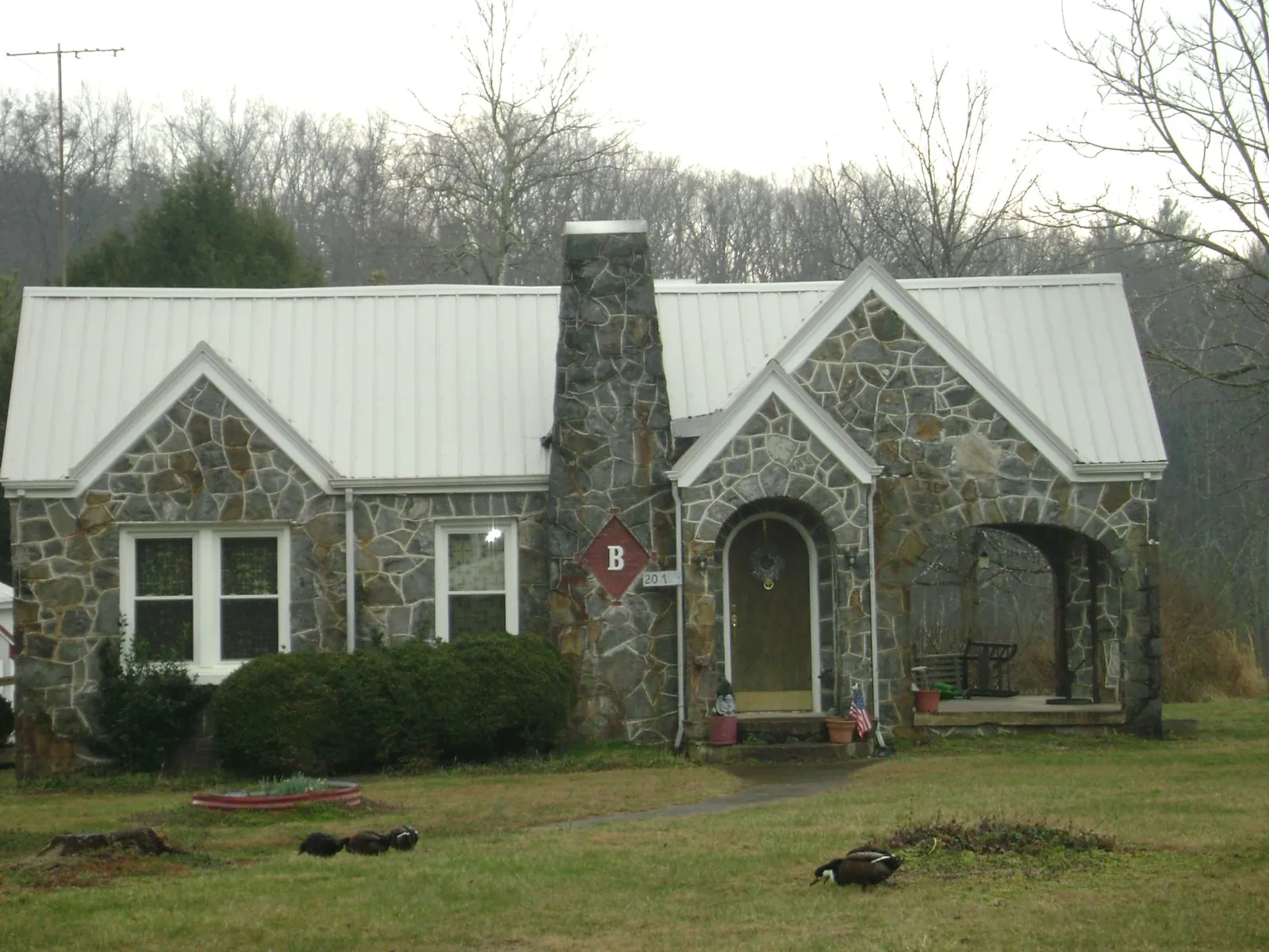 White metal roof on a stone cottage with steep gables in Akron